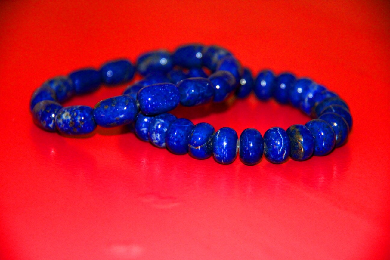 Two blue beaded bracelets on a red surface